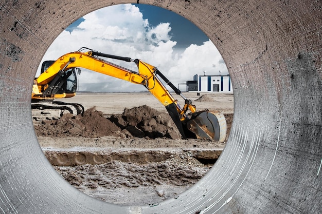 A powerful caterpillar excavator digs the ground against the evening sunset Earthworks with heavy equipment at the construction site Excavator in contrast against the sky