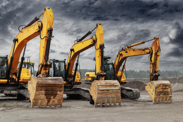 Powerful excavators at a construction site against a blue cloudy sky Earthmoving construction equipment Lots of excavators