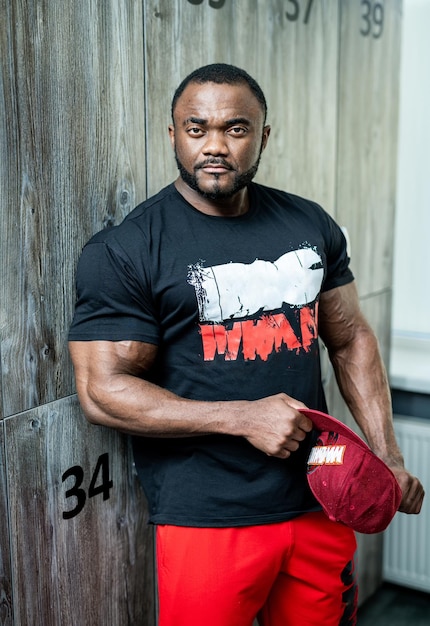 Powerful fitness man posing in gym Stylish strong man posing with cap