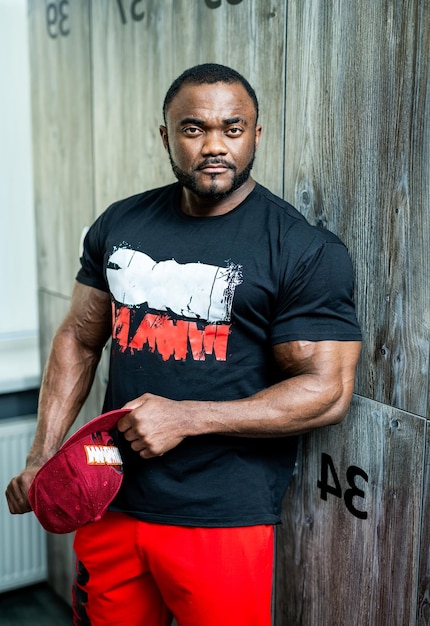 Powerful fitness man posing in gym Stylish strong man posing with cap