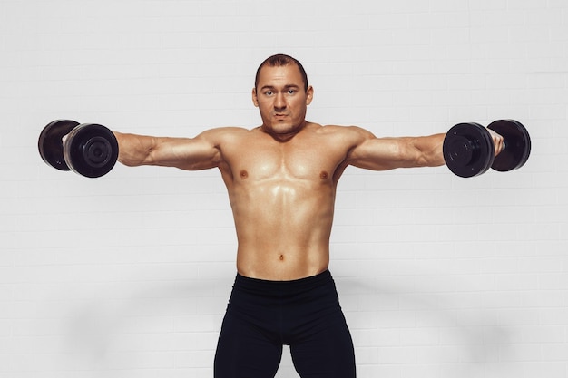 Powerful man doing the exercises with dumbbells photo of young man with good physique isolated on wh