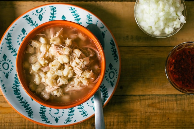 Pozole served in a deep dish on a wooden table Typical Mexican food made from corn