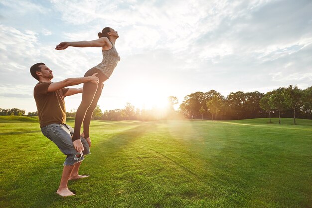 Practice of flying two people practicing acro yoga in nature on a sunny morning strong