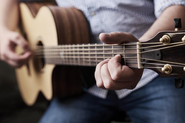 Practice makes perfect Cropped shot of an unrecognizable man playing an acoustic guitar at home