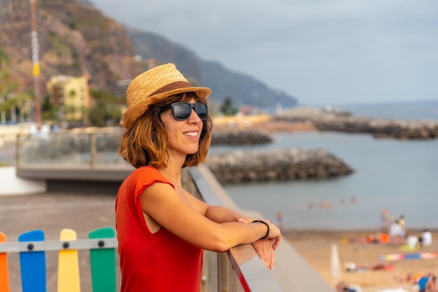 Praia da Calheta in summer young tourist girl in red dress on the beach Madeira Portugal