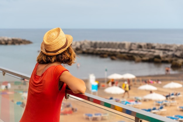 Praia da Calheta in summer A young woman tourist in a red dress looking at the beach Madeira Portugal