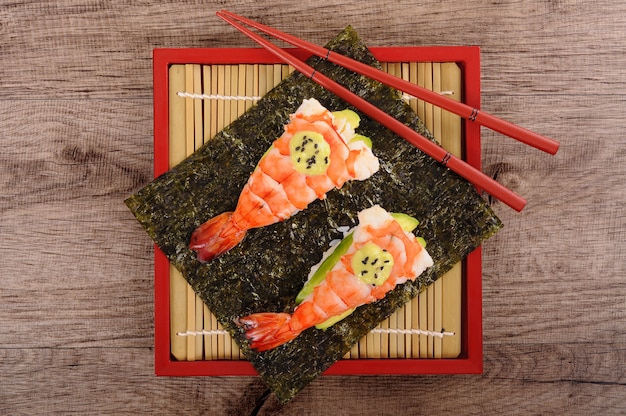 Prawn and avocado sushi with chopsticks, top view