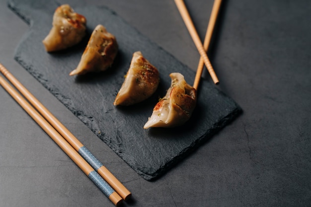 Prawn gyozas on a dark slate next to some chopsticks. Typical Asian dish. Top view..