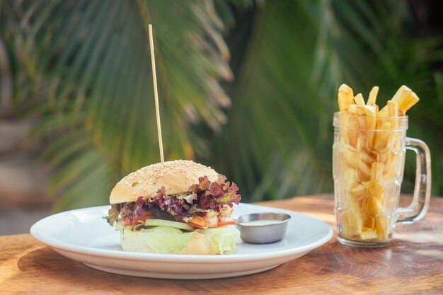 Photo prawns burger and french fry on table tropical sea palms tree and beach background