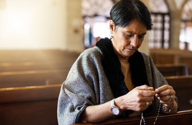 Pray senior woman and praying in church with a rosary for religion worship and God praise peaceful and calm Holy peace and prayer by Mexican female in chapel in Mexico for spiritual blessing