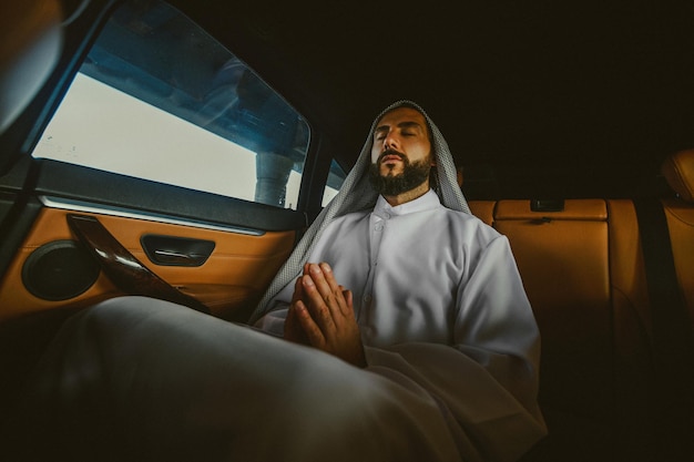 Praying in a car A young rich saudi in a leather car interior praying