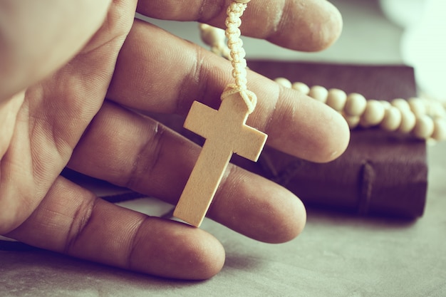 Praying hands of poor man with a rosary on on cement table prayer, rosary