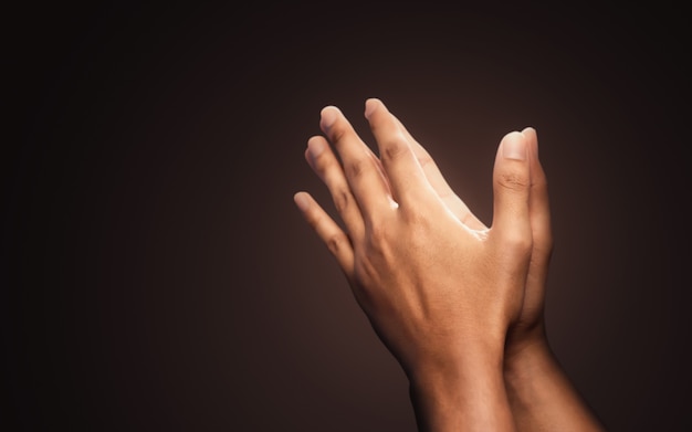 Praying hands with faith in religion and belief in God on dark background