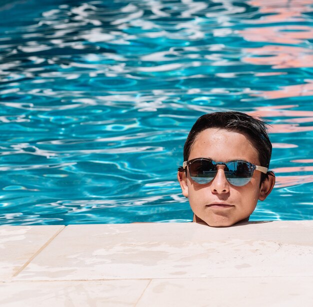 Pre-teens pose with sunglasses by the edge of the pool