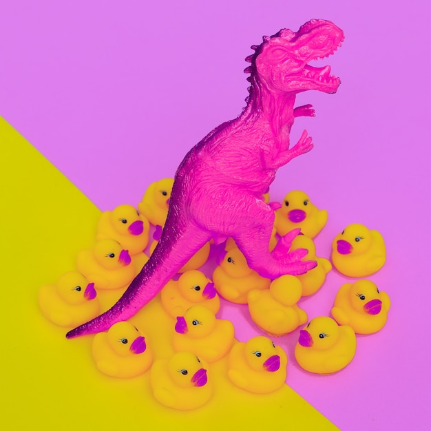 Predator Dinosaur toy and ducklings on colored background. Minimal flat lay art.