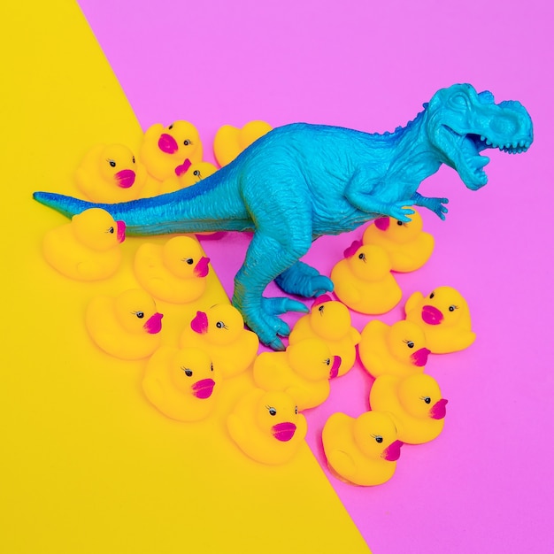 Predator Dinosaur toy and ducklings on colored background. Minimal flat lay