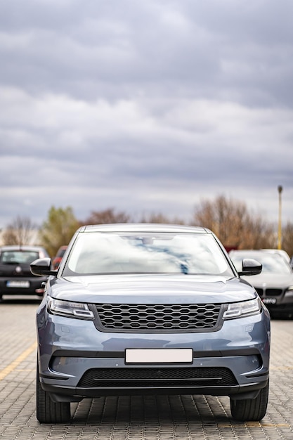 Predatory car headlight with blue lights and hood of powerful grey blue car sports car with matte grey paint and wheel with blue disc