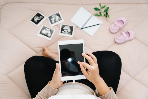 A Pregnancy dairy Top view of pregnant woman writing thoughts down with tablet for memoryxray image of her baby and shoesConcept of pregnancy Maternity prenatal care