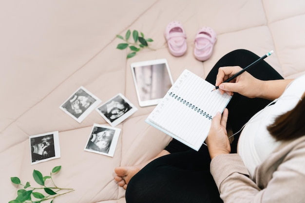 A Pregnancy dairyTop view of pregnant woman writing thoughts down in notebook for memoryxray image of her baby and shoesConcept of pregnancy Maternity prenatal care