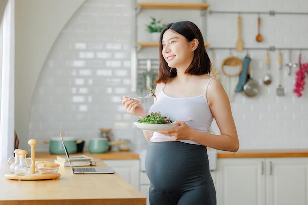 pregnancy healthy food and people concept close up of happy pregnant woman eating vegetable salad for breakfast in bed at home Child and Maternity prenatal care concept