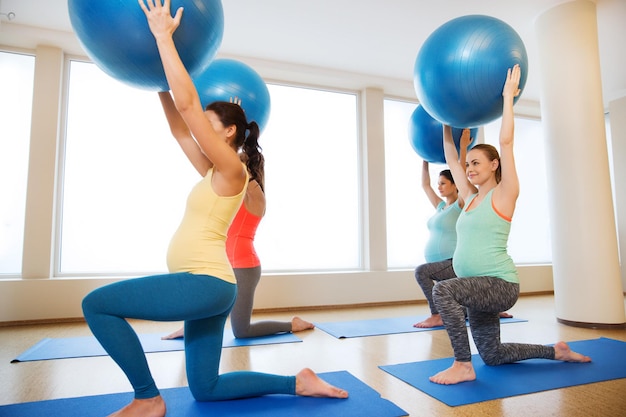 pregnancy, sport, fitness, people and healthy lifestyle concept - group of happy pregnant women exercising with ball in gym