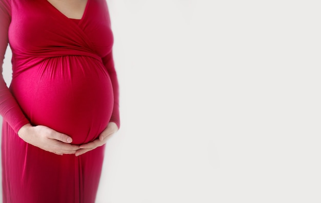 Pregnancy women holds her hands on her pregnant belly closeup