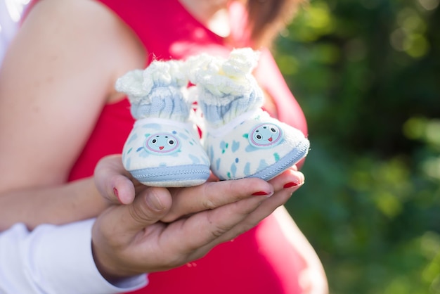 Pregnant couple holding knitted blue and white booties on the background of the tummy