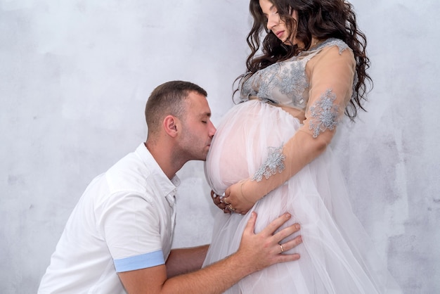 Pregnant couple. Man kissing his beautiful wife in belly. Waiting for a baby