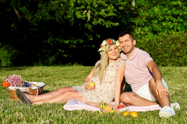 Pregnant couple on nature  park at a picnic in the summer