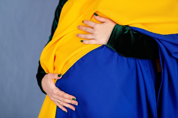 A pregnant girl holds the Ukrainian flag on her stomach and dreams of peace