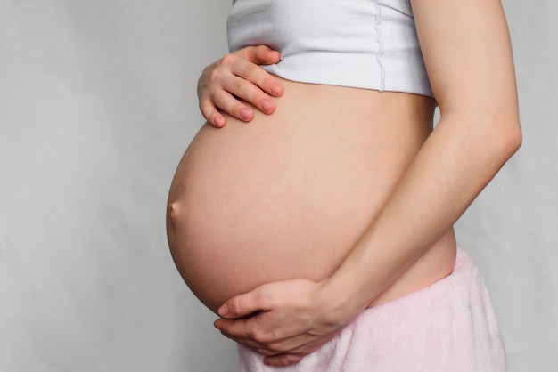 Pregnant girl hugging her belly with her hands