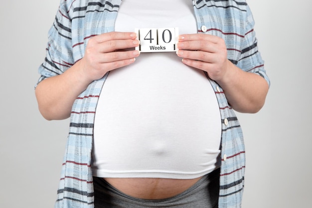 A pregnant girl keeps calendar over her stomach 40 weeks Concept the term is coming the time of birth