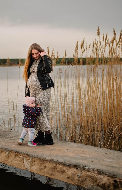 pregnant girl in nature spring lake the girl smiles happy mom mom and daughter are walking