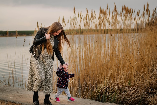 pregnant girl in nature spring lake the girl smiles happy mom mom and daughter are walking