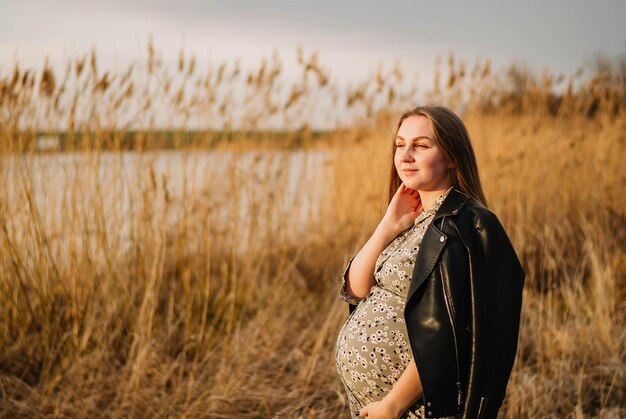 pregnant girl in nature spring reeds pregnant girl on the lake shore the girl smiles a happy mom