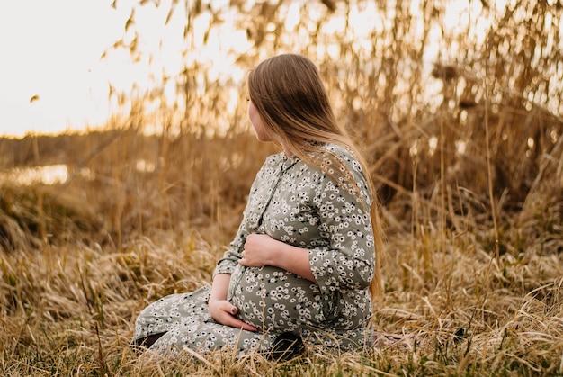 pregnant girl in nature spring reeds pregnant girl on the lake shore the girl smilesa happy mom