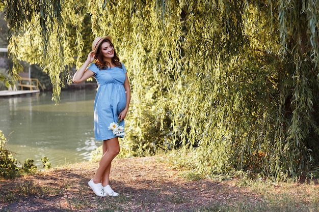 pregnant girl in the park with a bouquet of daisies