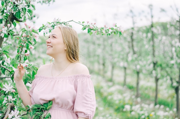 Pregnant girl in a pink dress in a flower garden