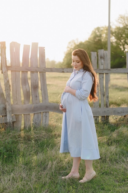 Pregnant girl in summer outdoors in the setting sun