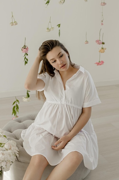 Pregnant girl in a white dress with peonies