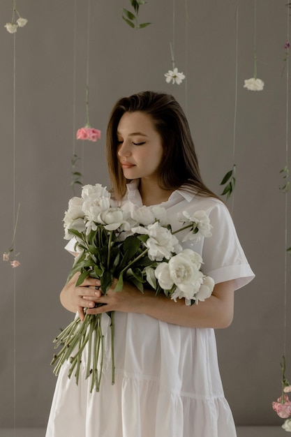 Pregnant girl in a white dress with peonies