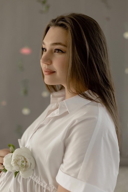 Pregnant girl in a white dress with peonies