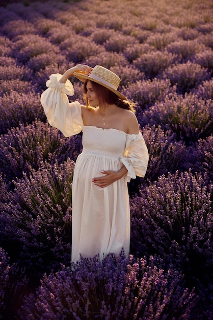 The pregnant girl with a hat in the lavender field on a sunset