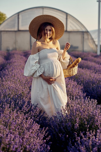 The pregnant girl with a hat in the lavender field on a sunset