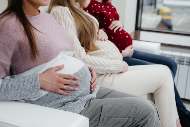 Pregnant girls hold their tummies with their hands in close-up. Prenatal class of pregnant girls