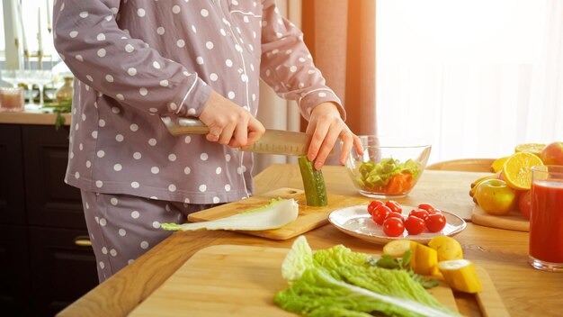 Pregnant housewife chops cucumber for vegetable salad