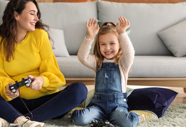 Pregnant mother with little daughter playing video games at home