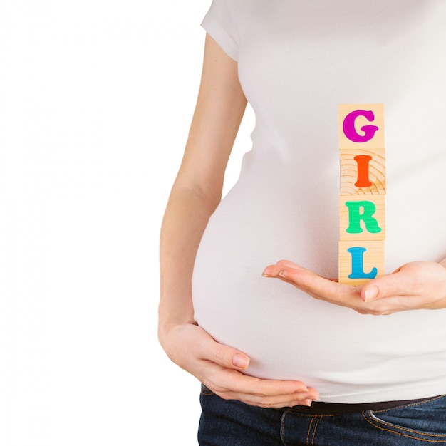 Pregnant woman belly with hands holding wooden blocks with girl sign isolated on white