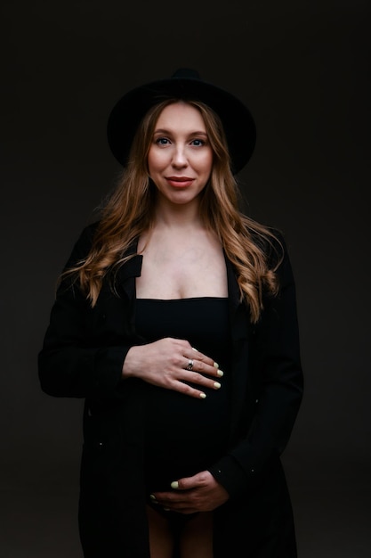 A pregnant woman in a black suit and a black hat. Space for copying. The concept of healthy digestion, lifestyle, IVF