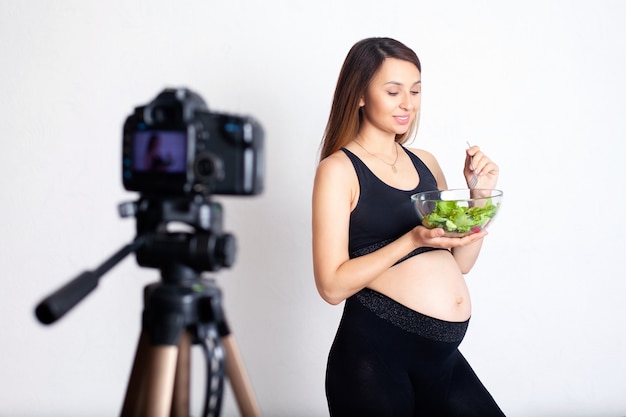 A pregnant woman blogger records a video on camera about proper nutrition during pregnancy